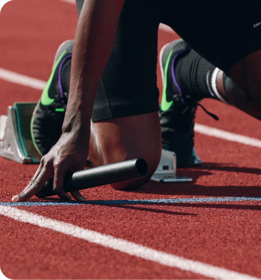 A close up of a runner's hand and feet in the starting position just before beginning a race on a track.